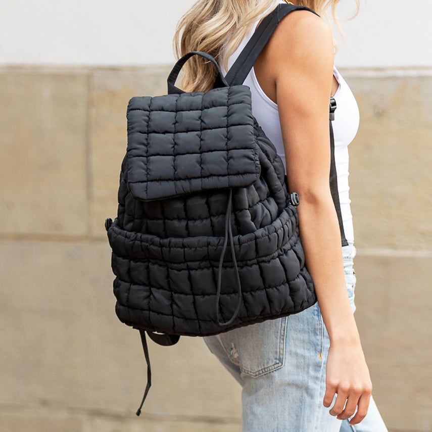 Quilted black puffer nylon backpack with silver hardware and dual drawstring-and-magnetic-flap closure