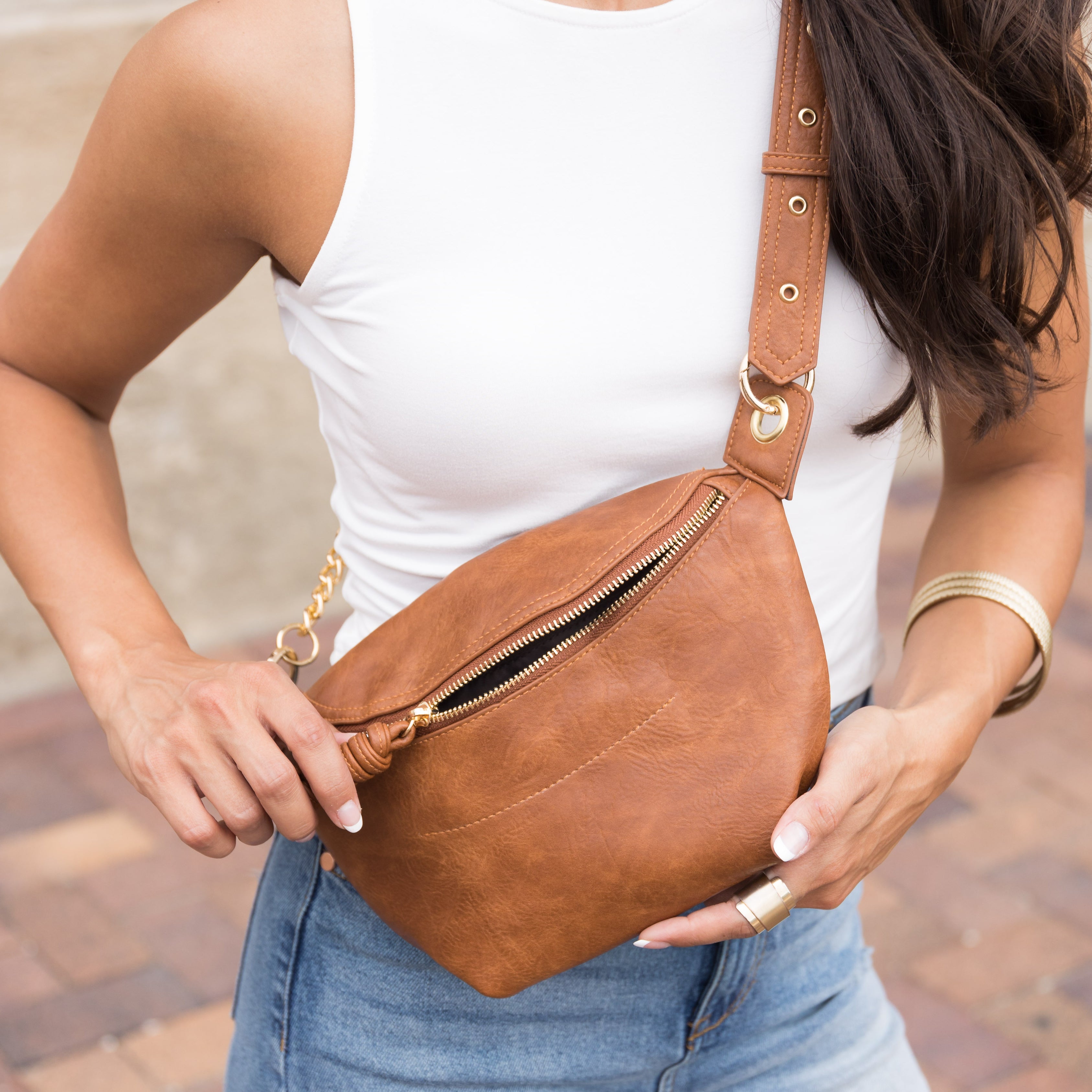 Convertible sling belt bag in distressed cognac vegan leather with gold O-ring clasp and chain strap detail