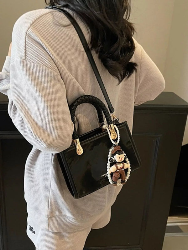 Structured black mini crossbody bag with braided top handles and gold hardware