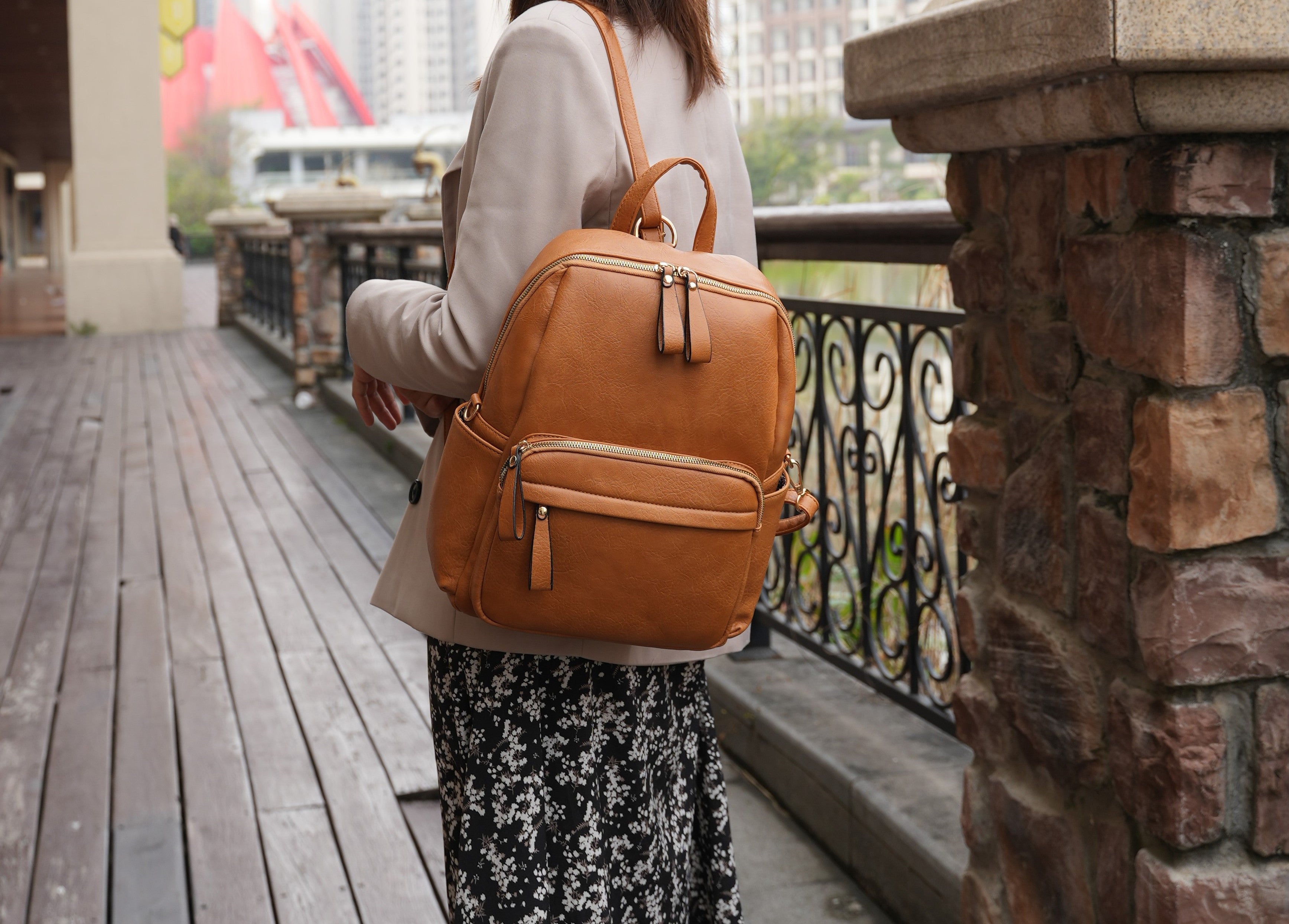 Structured vegan leather convertible backpack with gold hardware and multiple front zip pockets